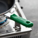 A green Choice silicone pan handle sleeve placed on a pot handle.