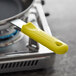 A yellow removable silicone sleeve on a pan handle.