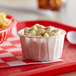 A red tray with a white Genpak paper bowl of macaroni and cheese and a basket of fries.