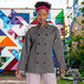 A woman wearing a slate grey Uncommon Chef long sleeve chef coat with 10 buttons.