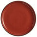 An Acopa Keystone Sedona Orange stoneware coupe plate with a black rim.