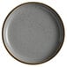 An Acopa Keystone granite gray stoneware coupe plate with a speckled rim.