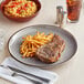 An Acopa Keystone stoneware plate with steak and french fries on it.