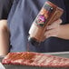 A person pouring McCormick Mesquite Seasoning on a piece of meat.