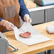 A person wearing gloves and using Choice White Butcher Paper to hold a piece of meat.