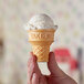 A hand holding a Keebler Eat-It-All ice cream cone filled with ice cream.