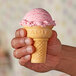A hand holding a Keebler Eat-It-All cake cone filled with pink and white swirled ice cream.