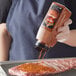 A person pouring McCormick Grill Mates BBQ seasoning on a piece of meat.