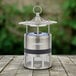 A silver and black round metal lantern with a decorative top sitting on a wooden table.