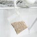 A white bag of Victor Pest M805 Scent-Away Natural Rodent Repellent hanging from a wire shelf.
