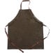 A brown San Jamar vinyl apron with brown straps on a counter.