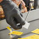 A person wearing black gloves uses a CDN Anti-Bacterial Thermometer Probe Wipe to clean a metal object.