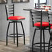 A Lancaster Table & Seating black ladder back swivel bar stool with a red cushion.