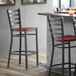 A Lancaster Table & Seating black finish ladder back bar stool with mahogany wood seat.
