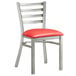 A Lancaster Table & Seating clear coat finish metal ladder back chair with red vinyl padded seat.