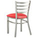 A Lancaster Table & Seating metal ladder back chair with a red vinyl cushion.