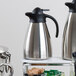 A Tablecraft stainless steel coffee carafe on a shelf in a hotel buffet.