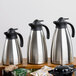 A close-up of a stainless steel Tablecraft coffee carafe with a black lid.