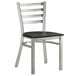 A Lancaster Table & Seating metal ladder back chair with a black seat.