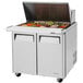 A Turbo Air 2 door mega top refrigerated sandwich prep table on a counter with food trays.