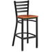 A Lancaster Table & Seating black metal ladder back bar stool with a cherry wood seat.