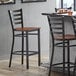 A Lancaster Table & Seating distressed copper ladder back bar stool with an antique walnut wood seat.