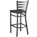 A black metal Lancaster Table & Seating ladder back bar stool with a black wood seat.