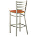 A Lancaster Table & Seating metal ladder back bar stool with a wood seat.