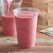 A pink smoothie being poured into a Fabri-Kal Greenware plastic cup.