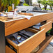 An Astella Indu+ outdoor mobile bistro island with a wooden counter, sink, and grill.