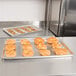 A Vollrath Wear-Ever aluminum sheet pan with perforated bread and croissants on it.