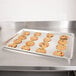 A Vollrath aluminum perforated sheet pan of cookies on a metal surface.