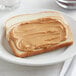 A piece of toast with REESE'S Creamy Peanut Butter spread on it.