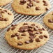 A close-up of a chocolate chip cookie on a cooling rack.