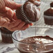 A person pouring Guittard organic bittersweet chocolate over a cupcake.