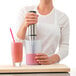 A woman using an iSi translucent silicone measuring cup to make a smoothie with a blender.