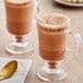 Two glass mugs of Guittard sweet ground chocolate powder with spoons.