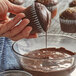 A person pouring Guittard Oban chocolate over a cupcake.