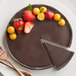 A chocolate cake with strawberries and cherries on top on a plate with a fork.