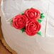 A white cake with red frosting decorated with Ateco cake marker slices and roses.