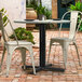 A Lancaster Table & Seating black outdoor table base with chairs on a brick patio.