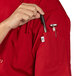 A person holding a pen in the pocket of a red Uncommon Chef short sleeve chef coat.