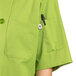A close up of the pocket on a white Uncommon Chef South Beach short sleeve chef coat with buttons.