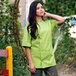 A woman wearing a green Uncommon Chef short sleeve chef coat with an avocado design.
