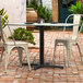 A Lancaster Table & Seating Excalibur outdoor table base on a brick patio with chairs.