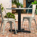 A Lancaster Table and Seating black outdoor table base with a round table and two white chairs on a brick patio.