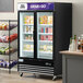An Avantco swing glass door merchandiser freezer with LED lighting and customizable panel shelves full of food.