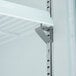 A metal shelf with a metal bracket inside an Avantco glass door merchandiser freezer.