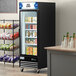 An Avantco black swing glass door merchandiser freezer with LED lighting and customizable panel.