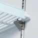 A metal shelf with a metal bar and metal corners in a white Avantco GDC-23-HC merchandising refrigerator.